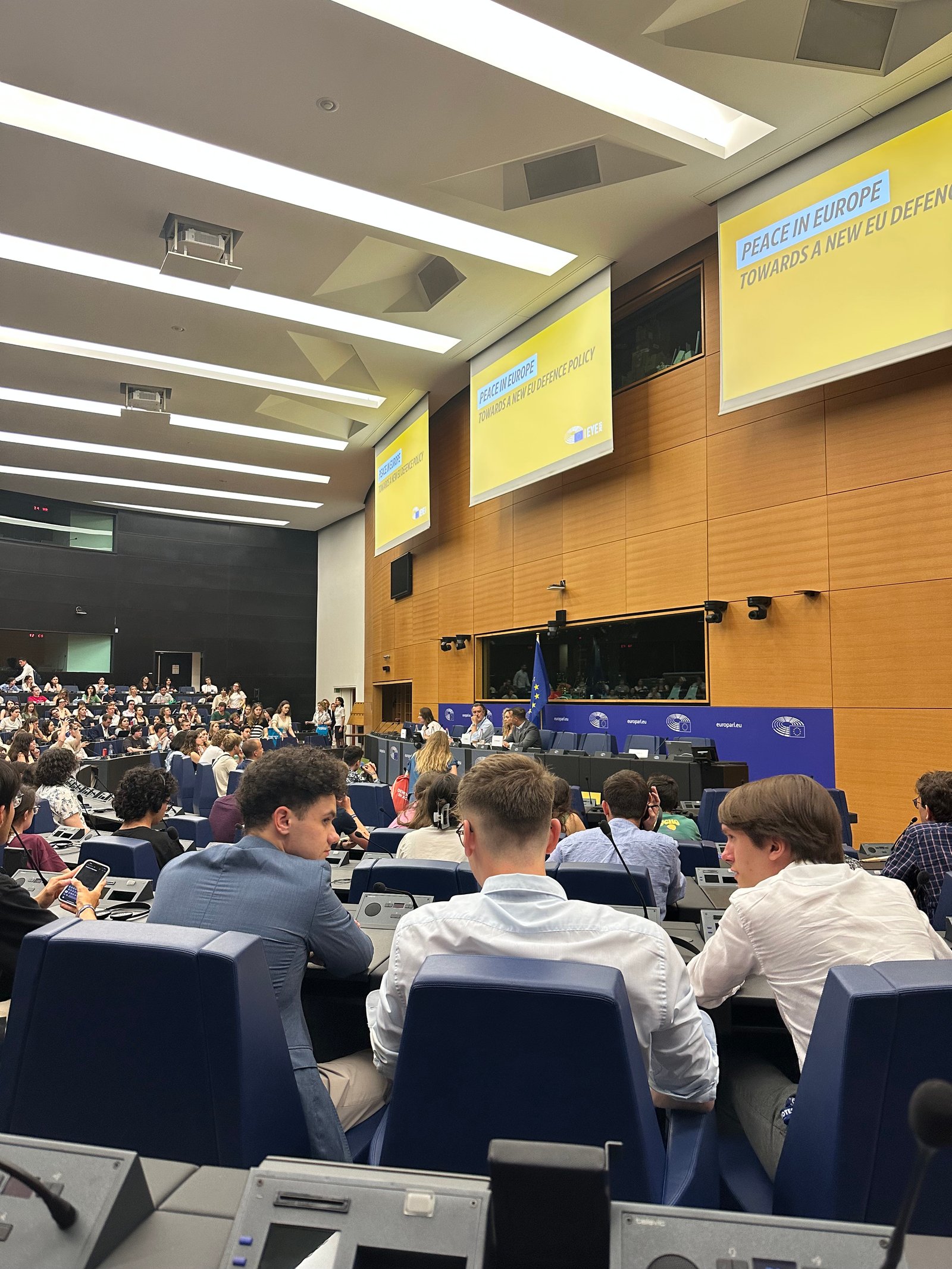 NGYA delegates at a European Parliament youth session on EU defence policy, seated at delegate desks