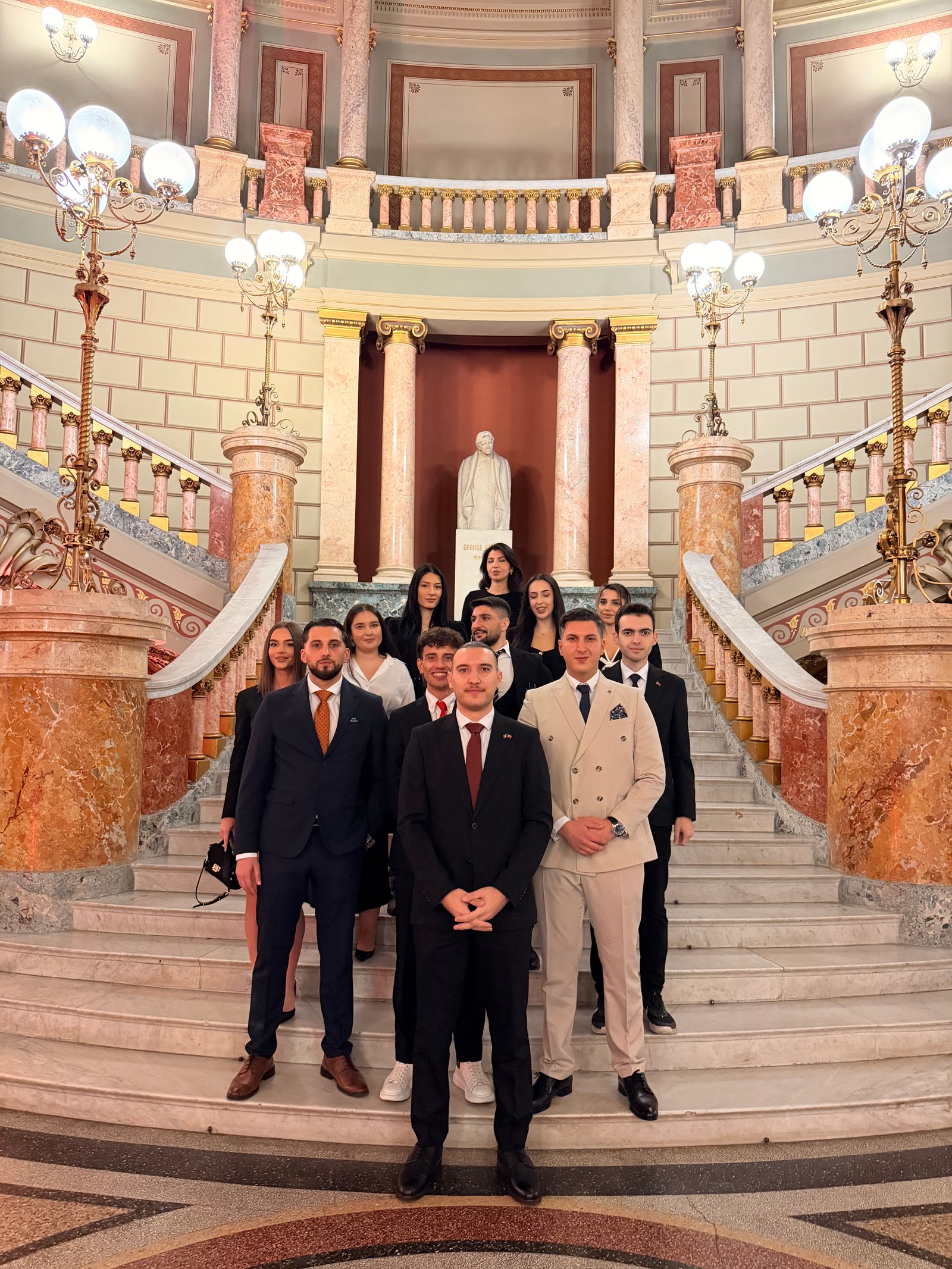 A group of NGYA members standing together on a grand marble staircase inside a historic building